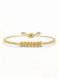 La imagen présente un bracelet élégant et sophistiqué pour femme. Il est composé d'une chaîne en boîte ajustable en acier inoxydable plaqué or 18 carats. Le design met en valeur un charme central en forme de feuille, orné de cristaux brillants CZ (Cubic Zirconia). La chaîne est ajustable, permettant un ajustement parfait à différents poignets, grâce à une perle coulissante qui facilite la personnalisation de la taille. Le bracelet est posé sur une surface élégante, avec un fond gris neutre qui met en avant 