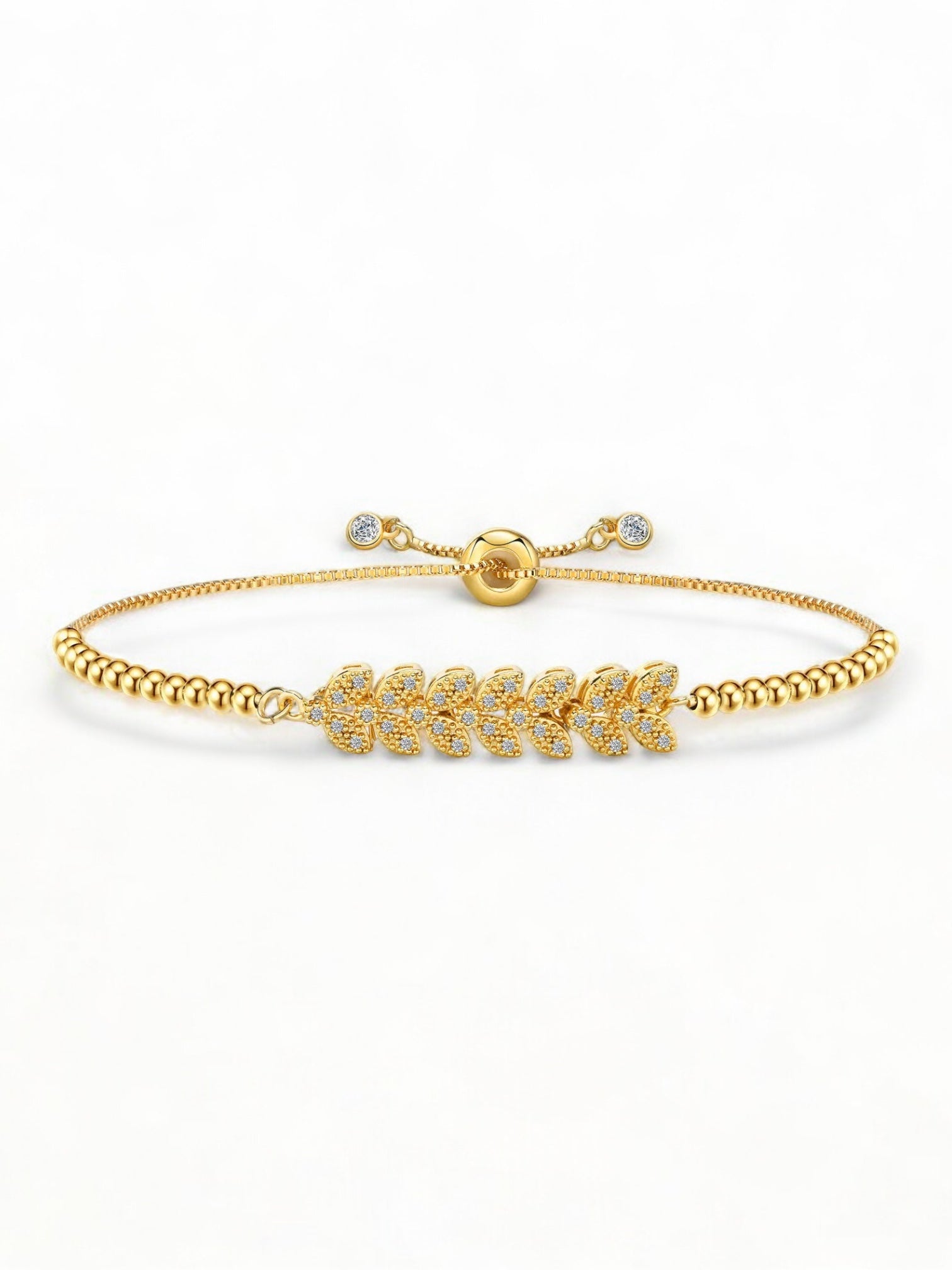 La imagen présente un bracelet élégant et sophistiqué pour femme. Il est composé d'une chaîne en boîte ajustable en acier inoxydable plaqué or 18 carats. Le design met en valeur un charme central en forme de feuille, orné de cristaux brillants CZ (Cubic Zirconia). La chaîne est ajustable, permettant un ajustement parfait à différents poignets, grâce à une perle coulissante qui facilite la personnalisation de la taille. Le bracelet est posé sur une surface élégante, avec un fond gris neutre qui met en avant 